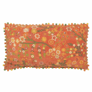Coussin rectangle en velours orange avec fleurs et pompons.
